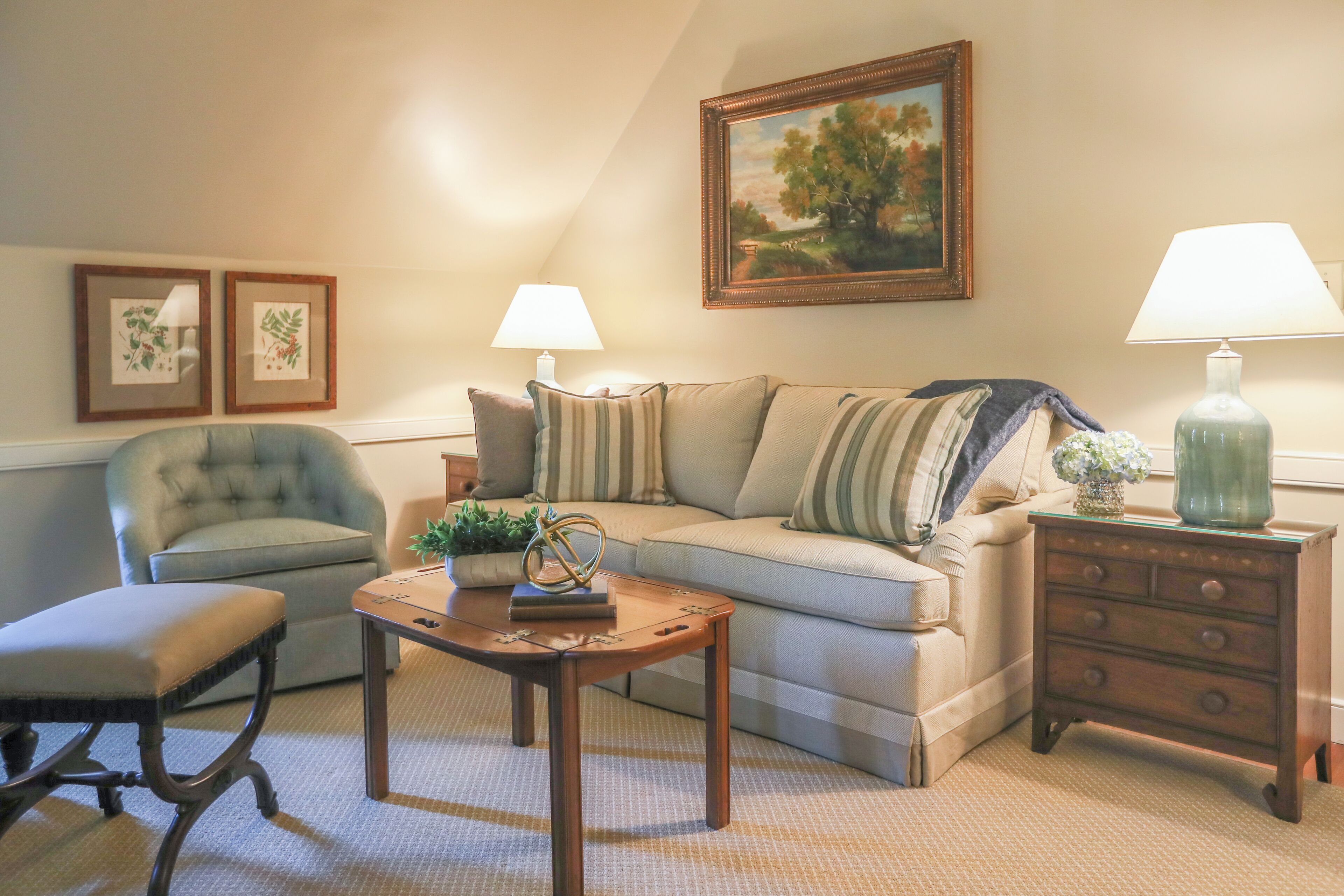A living room with a sofa, armchair, coffee table, and side table with lamps.