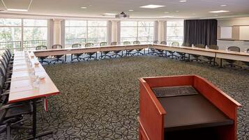 Une salle de conférence équipée d’une longue table, de chaises, d’un pupitre et d’un écran de projection.