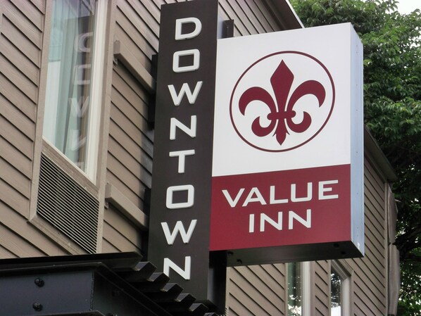A sign for the Downtown Value Inn, featuring a fleur-de-lis logo and the inn's name.