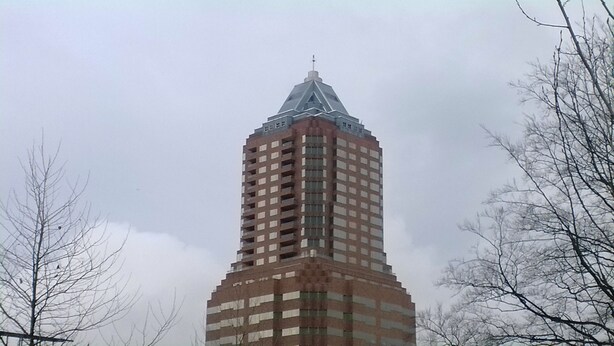 A tall, rectangular building with a pointed roof and a cross at the top, surrounded by bare trees. - Downtown Value Inn (Portland)