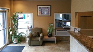A room with a large window, a chair, a small table, and a potted plant. - Downtown Value Inn (Portland)