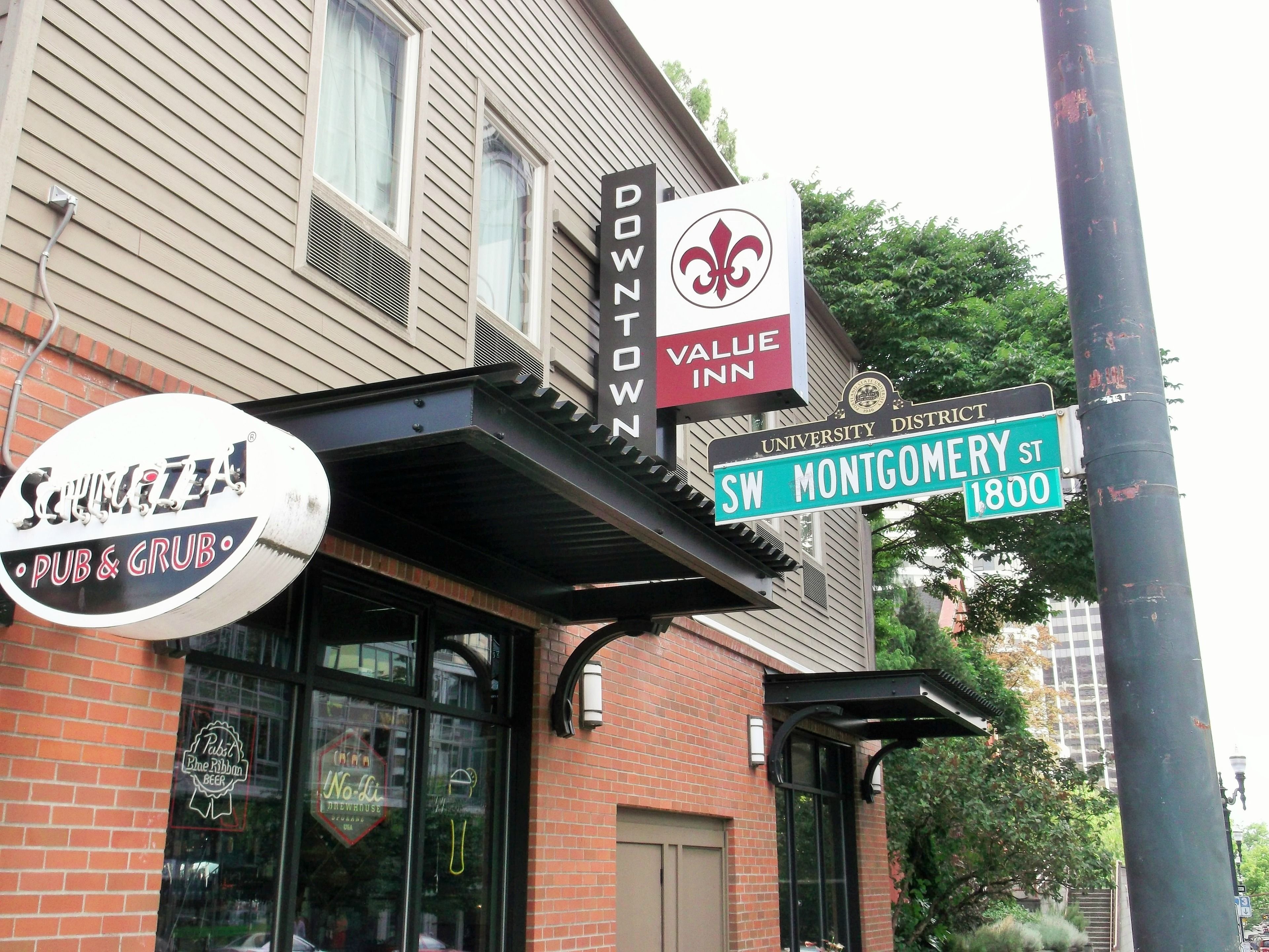 A building with a sign for 'Schmita Pub & Grub' and 'Downtown Value Inn' on the street corner.
