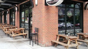 A brick building with a sign reading "Schmelt Pub & Grub" and outdoor wooden tables and chairs. - Downtown Value Inn (Portland)