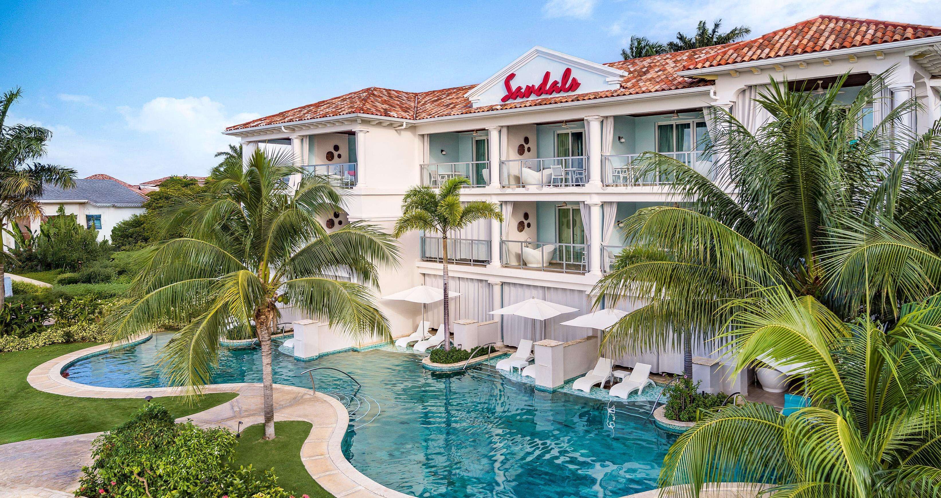 A hotel with a swimming pool surrounded by palm trees and lounge chairs.