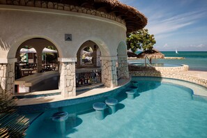 A poolside bar with stone arches, a bar counter, and a seating area with umbrellas.