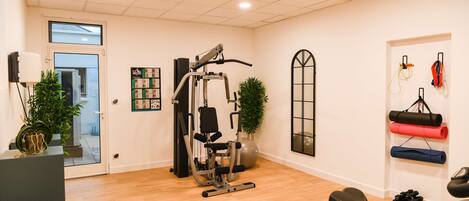 Un gimnasio en casa con barra de dominadas, bicicleta estática y varios pesas.