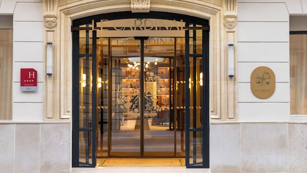 A hotel entrance with a glass door, a sign reading "LE CARDINAL," and a plaque with the hotel's name. - Hotel Le Cardinal (Paris)
