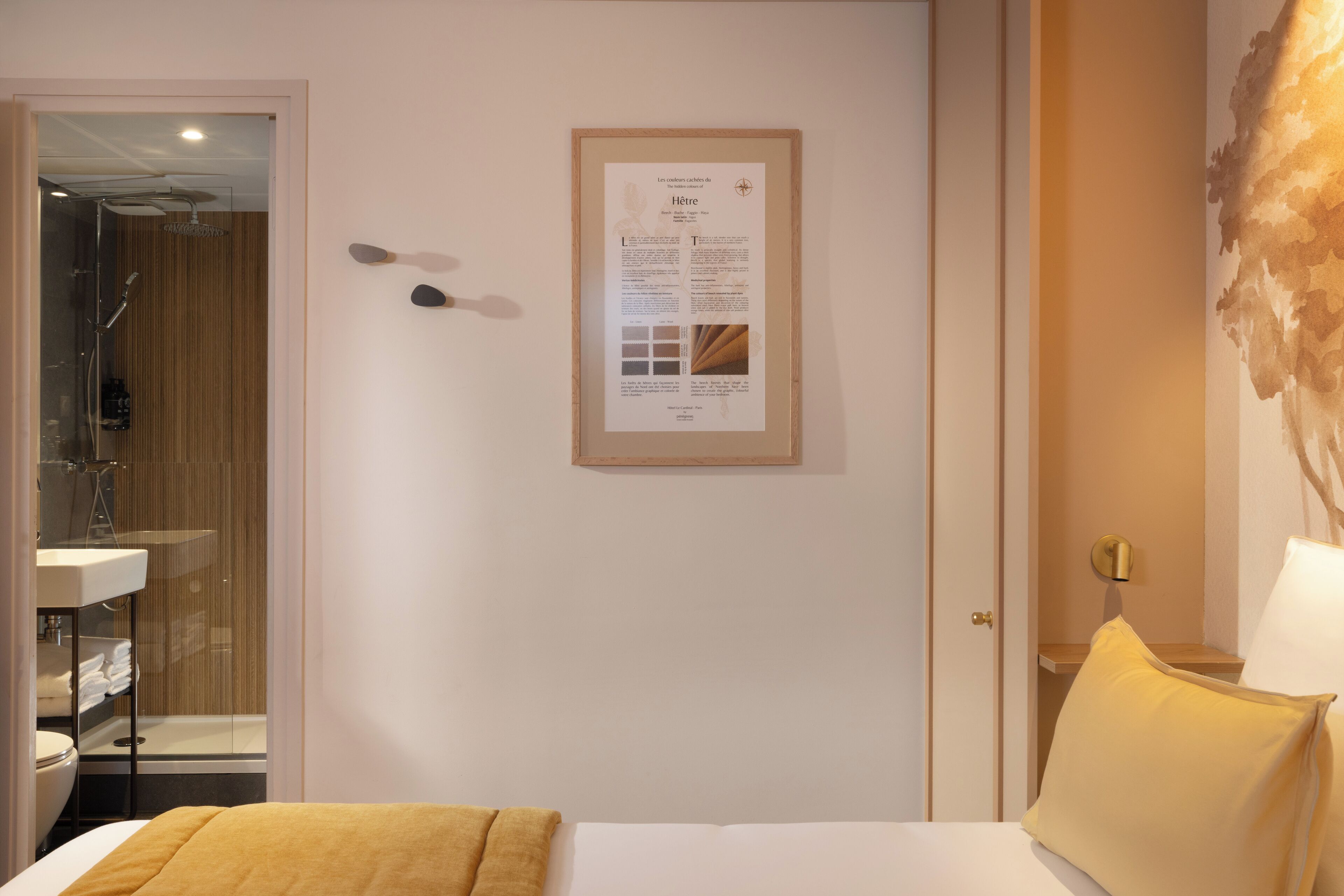 Ein Hotelzimmer mit einem Bett, einem Nachttisch mit Lampe, einem gerahmten Informationsplakat an der Wand und einem durchgegangenes Badezimmer.