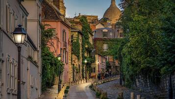 A cobblestone street lined with historic buildings, including a prominent tower and a church dome.