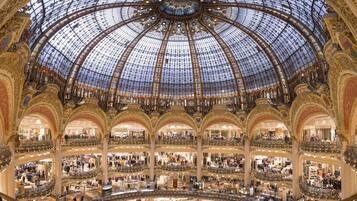 A multi-level shopping mall with ornate architecture and a glass dome ceiling.