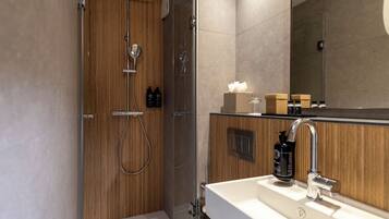 A modern bathroom with a wooden vanity, a large mirror, and a glass-enclosed shower.