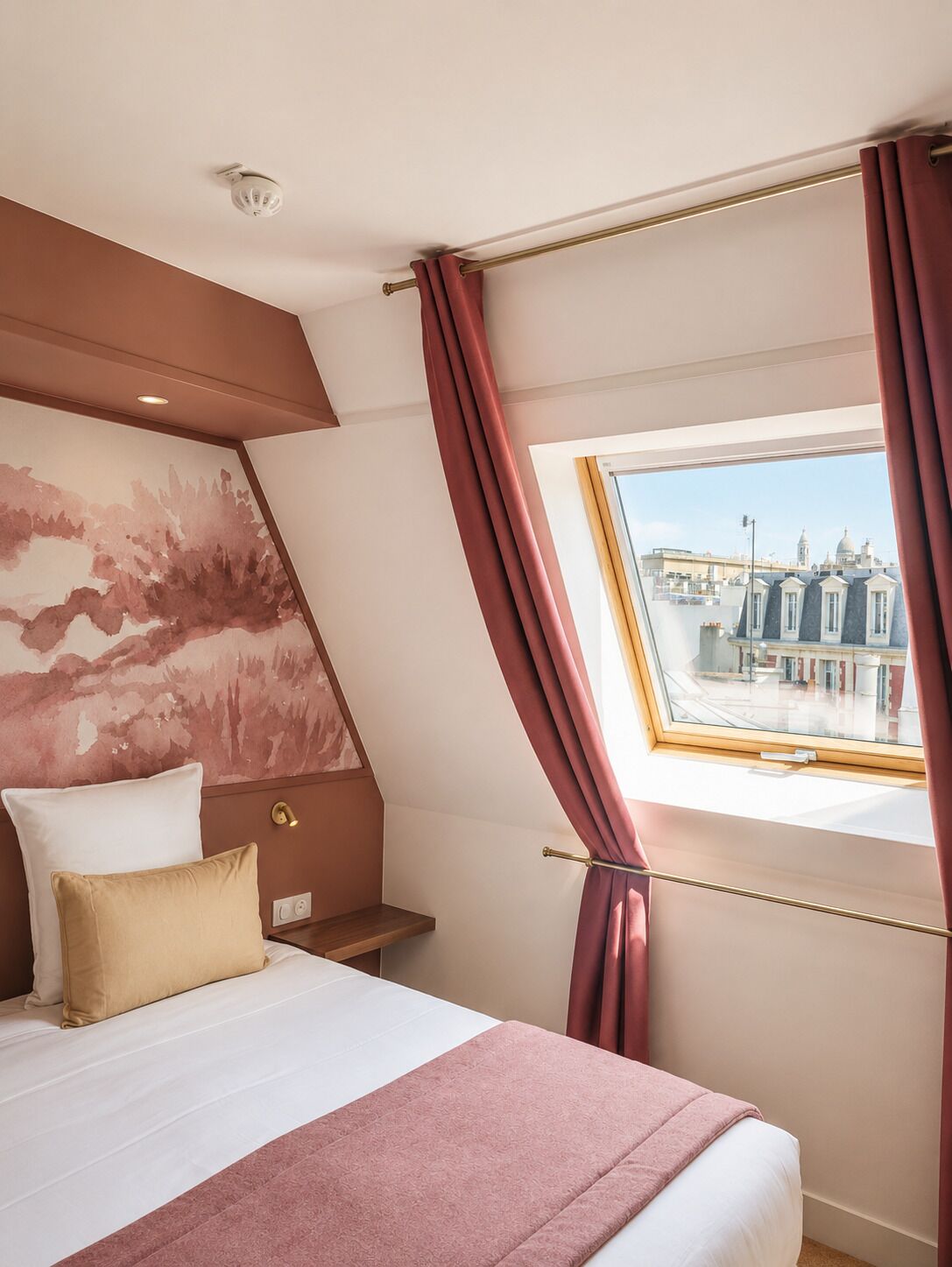A bedroom with a bed, a nightstand, a window with curtains, and a city view.