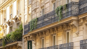 A building with ornate architectural details, a sign reading "LE CARDINAL," and a gated entrance. - Hotel Le Cardinal (Paris)