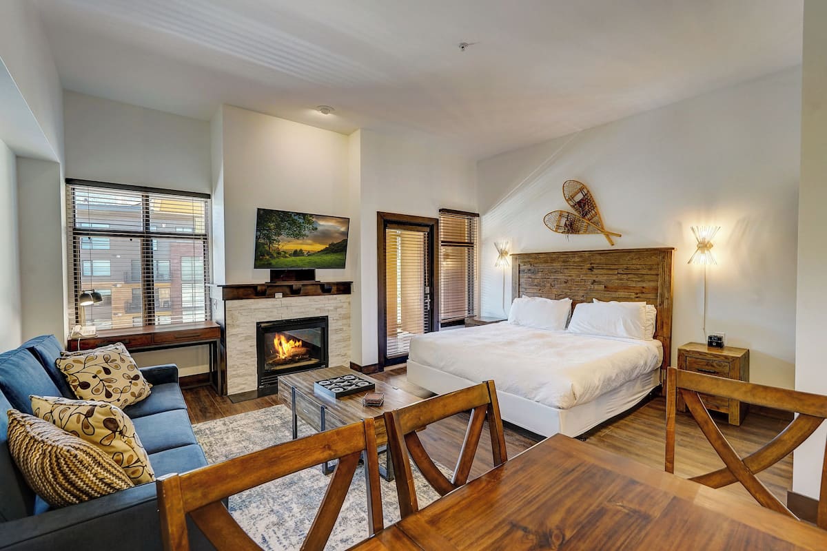 Een moderne slaapkamer met een groot bed, een open haard, een bank en een eettafel.