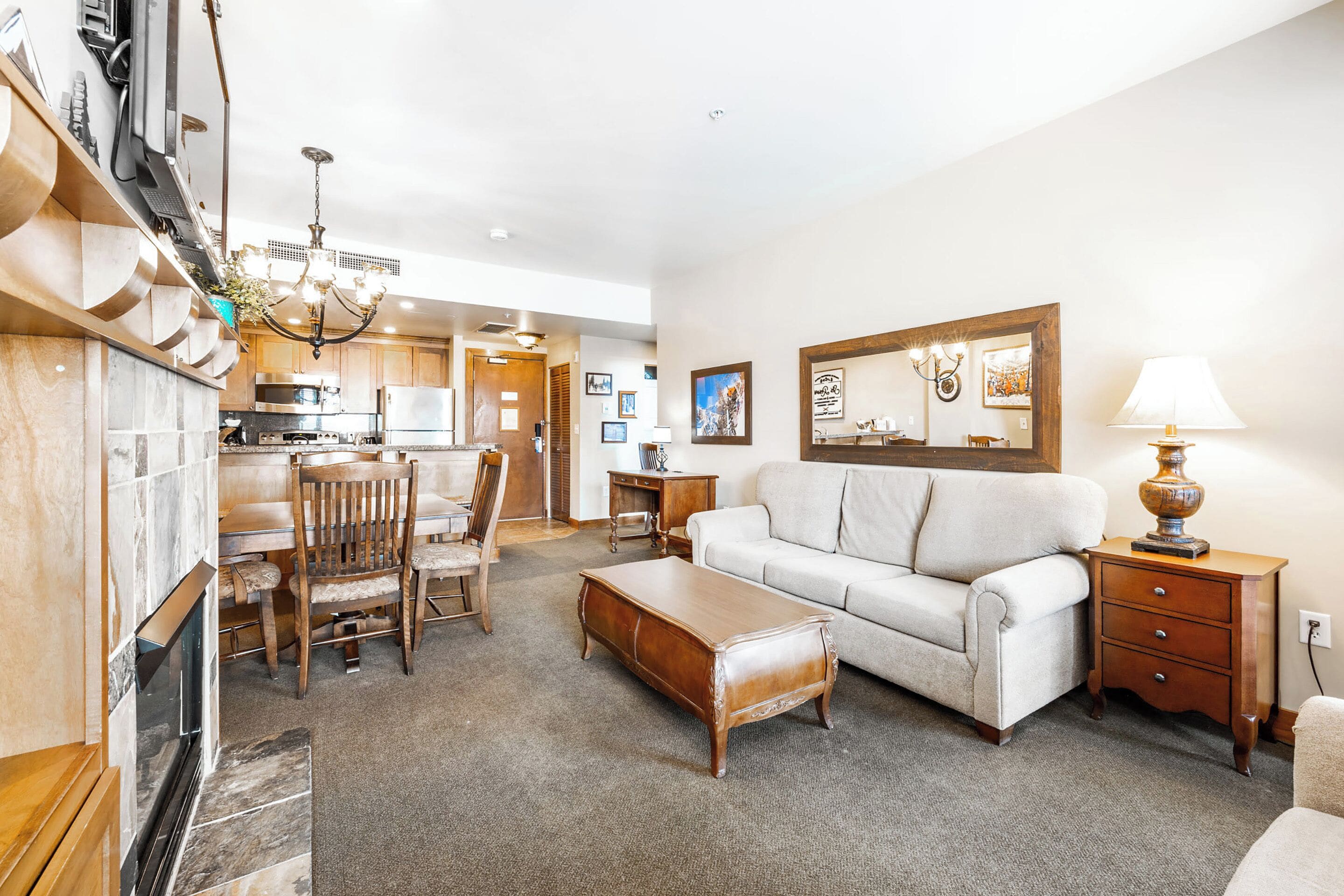 A spacious living area with a sofa, ottoman, and dining table set.