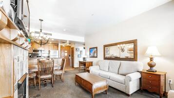 A spacious living area with a sofa, ottoman, and dining table set.