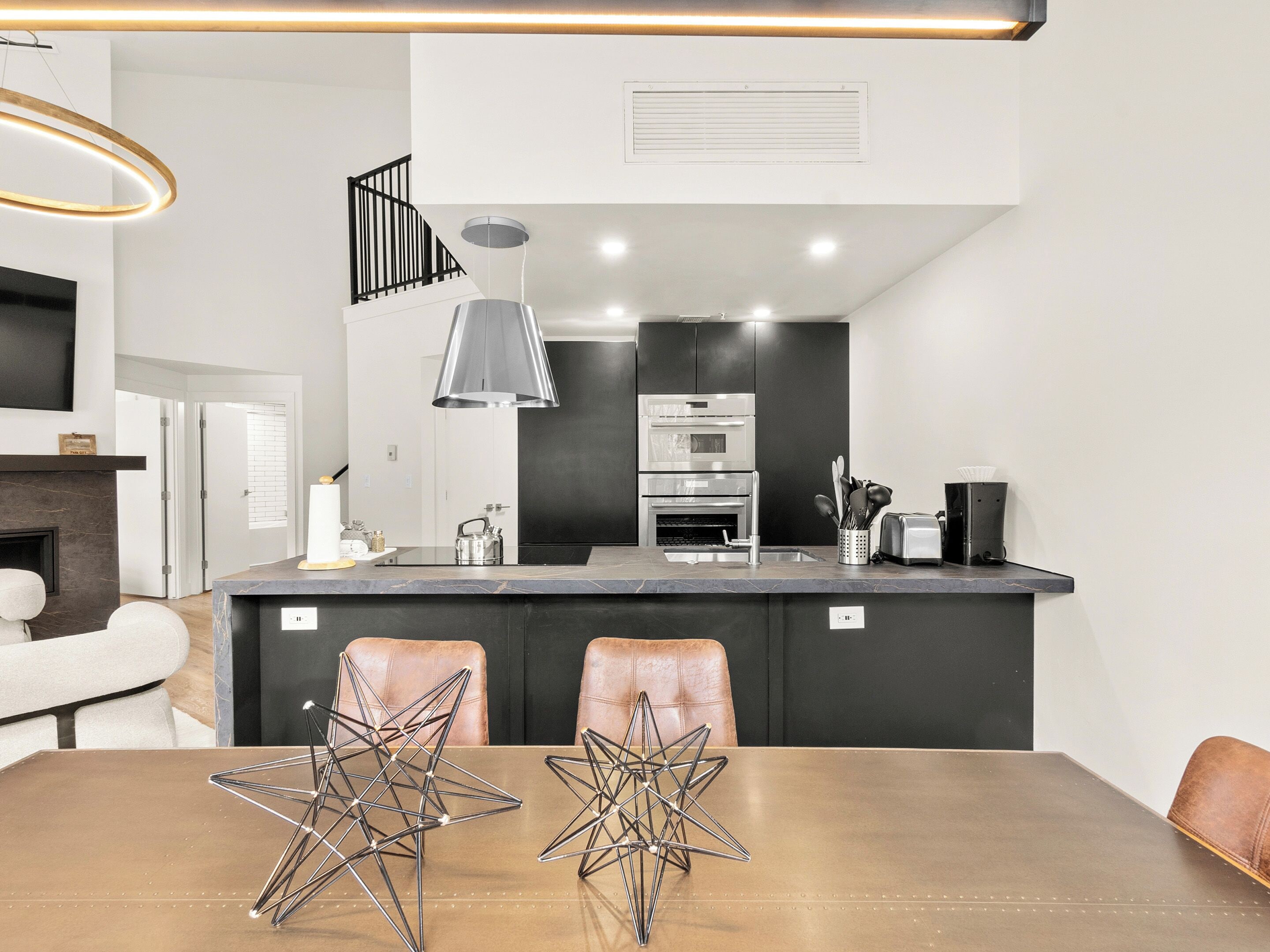 Una cocina moderna con una isla central, electrodomésticos de acero inoxidable y un comedor con un centro de mesa en forma de estrella.