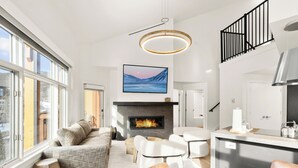 Una sala de estar moderna con chimenea, un comedor y una cocina con una isla grande.