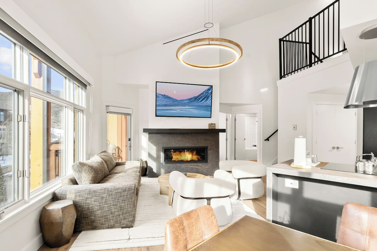 Een moderne woonkamer met een open haard, een eethoek en een keuken met een groot kookeiland.