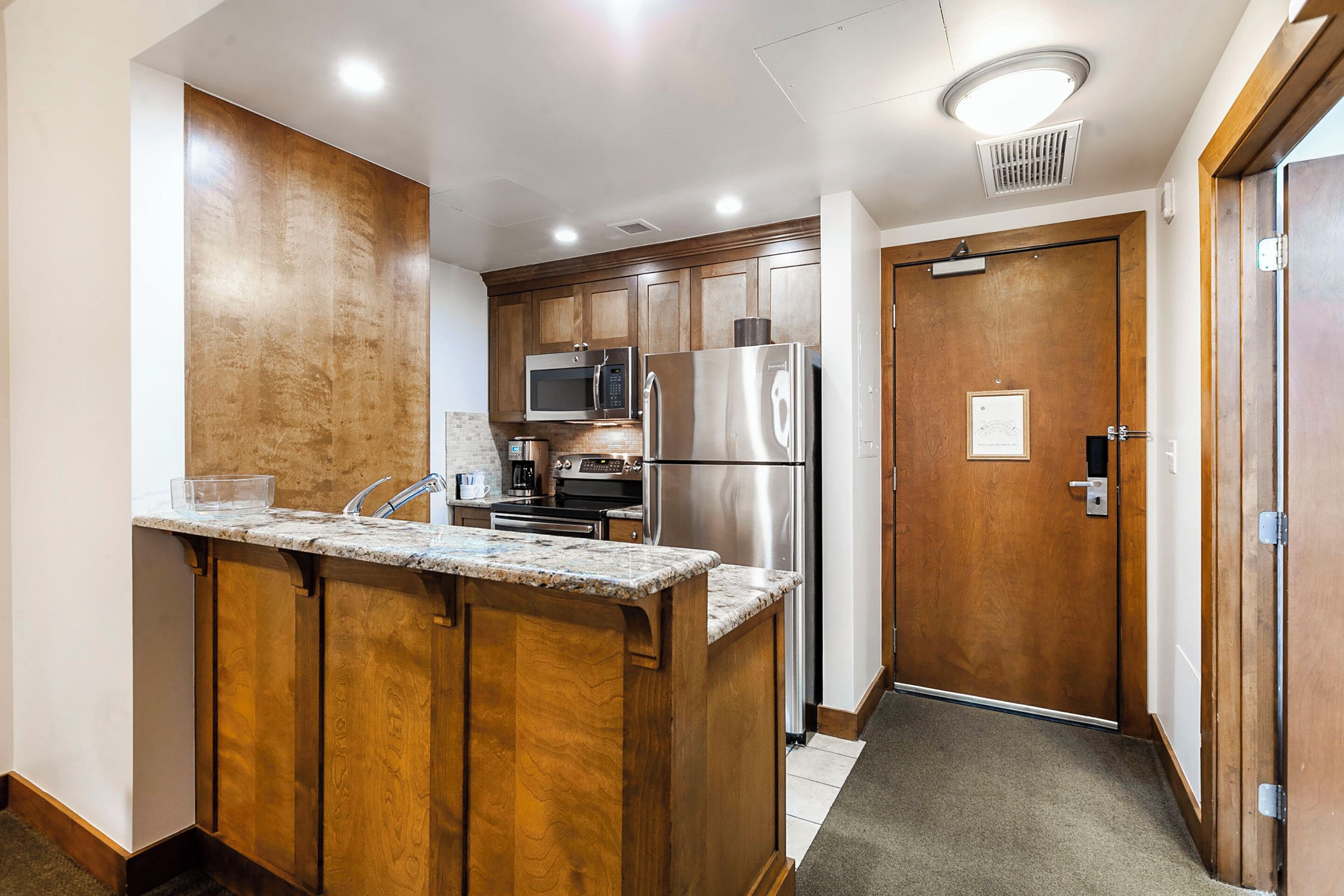 A compact kitchen with wooden cabinets, stainless steel appliances, and a built-in island.