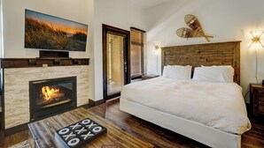 Ein Schlafzimmer mit einem großen Bett, einem Kamin, einem Fernseher und einem hölzernen Kopfteil.