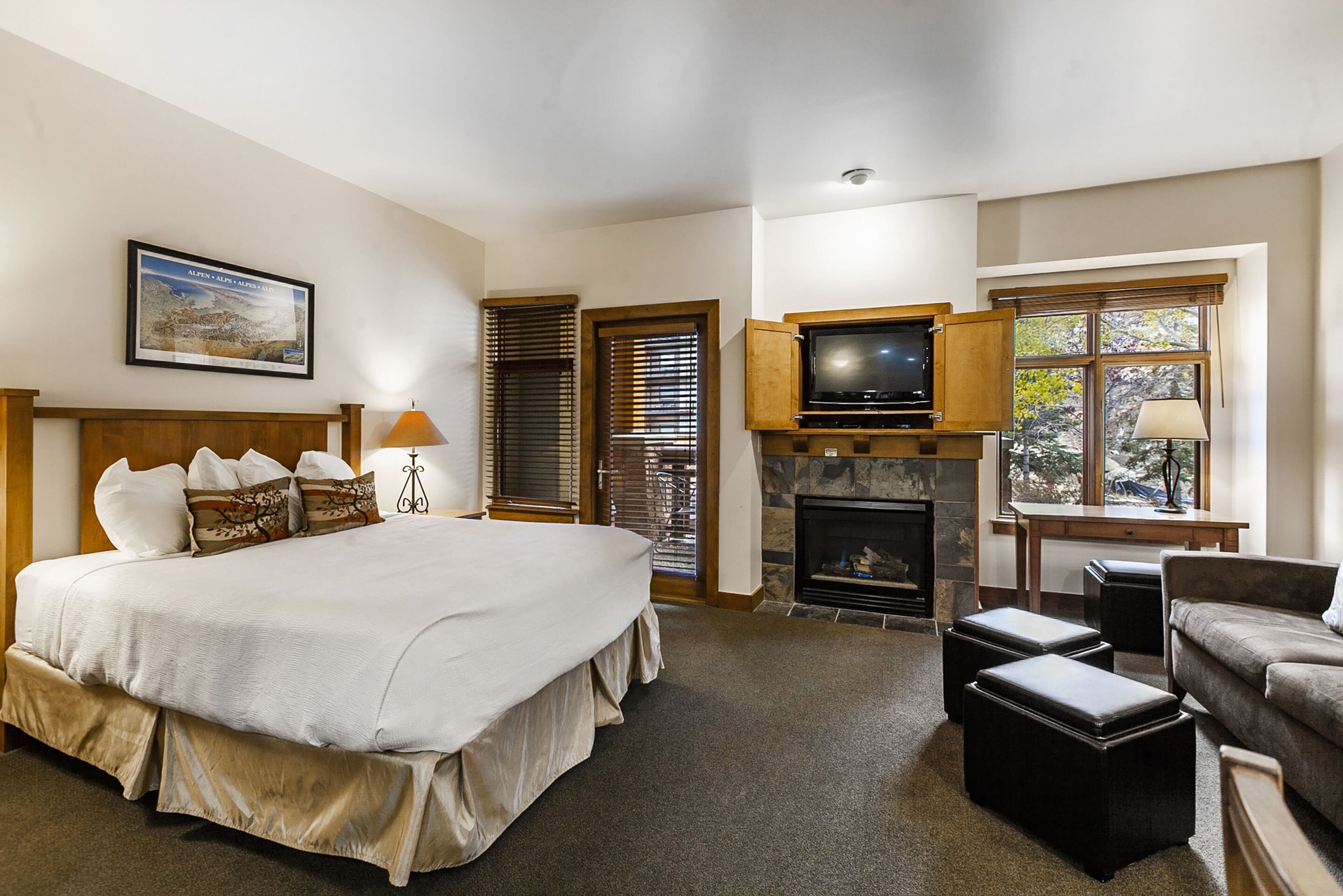 A bedroom with a large bed, a fireplace, a television, and a sofa.