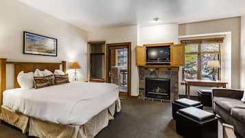 A bedroom with a large bed, a fireplace, a television, and a sofa.