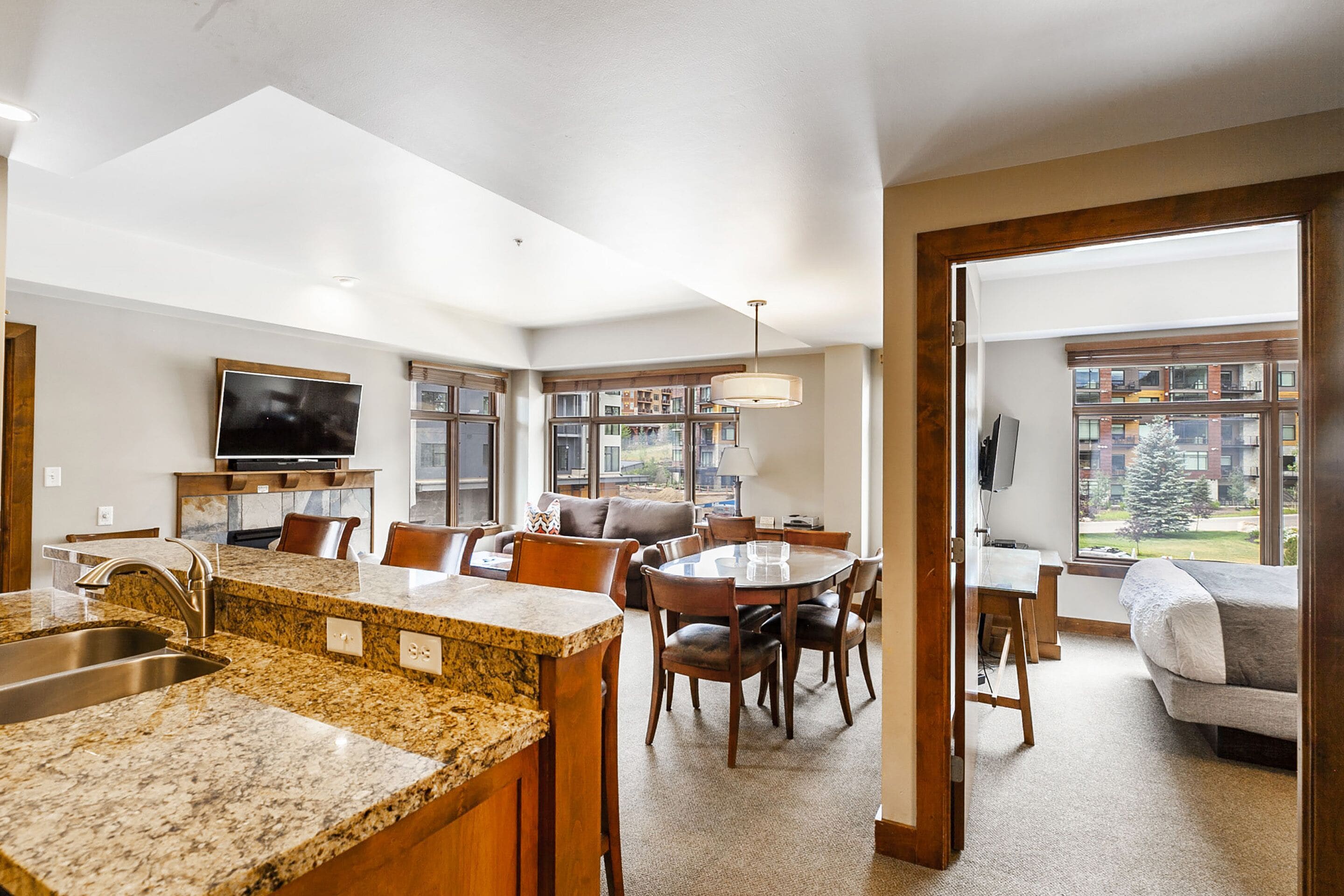 A modern kitchen with granite countertops, a built-in oven, and a dining area with a wooden table and chairs.