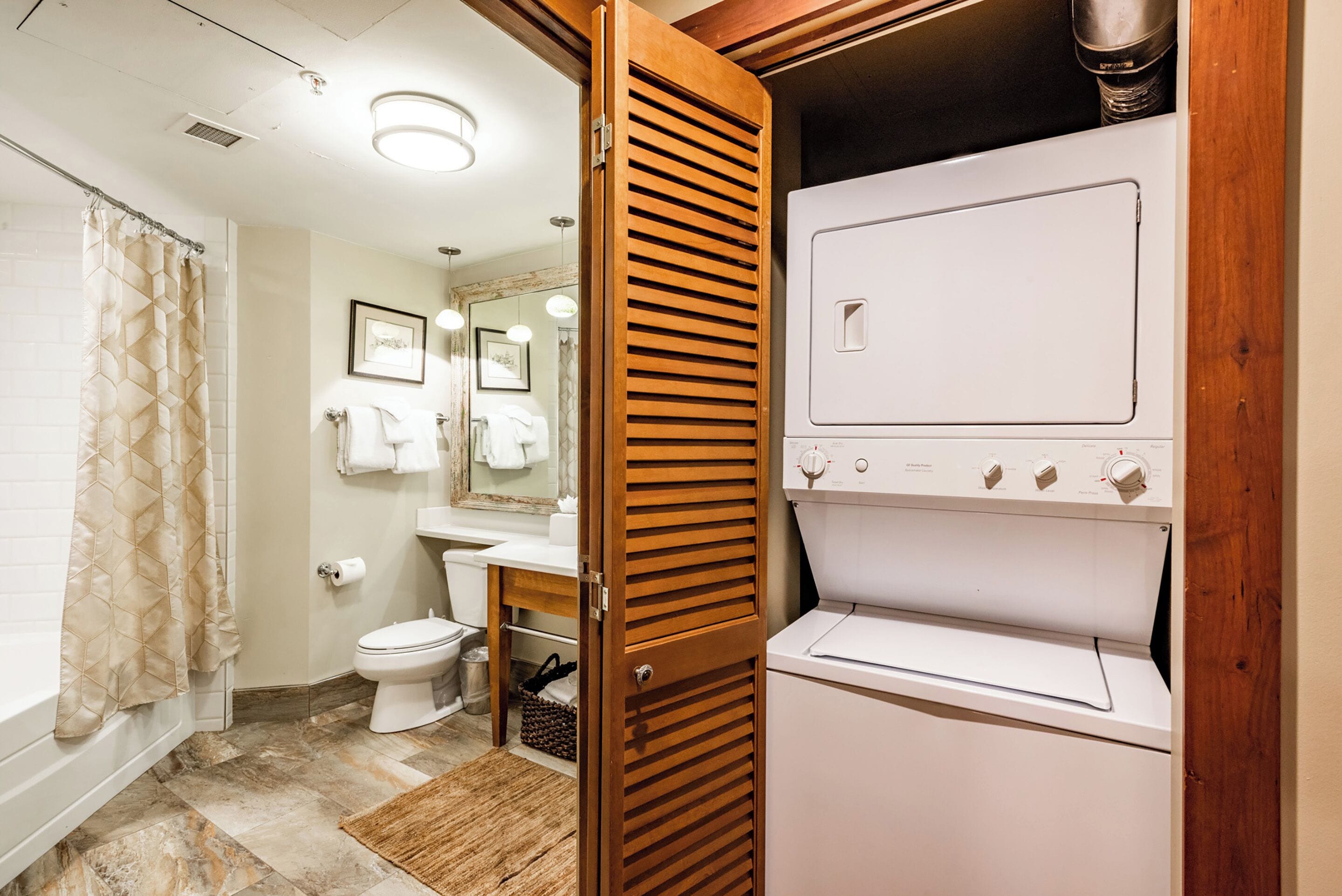 Un baño con ducha, inodoro, lavabo y lavadora secadora incorporada.