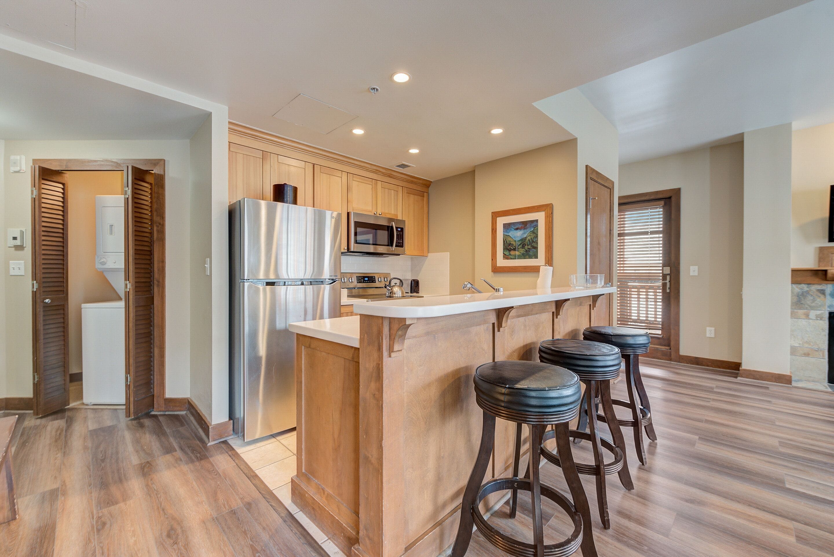 Una cocina moderna con armarios de madera, electrodomésticos de acero inoxidable y una isla central con taburetes de bar.