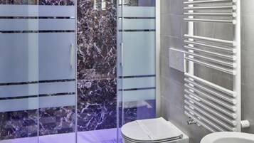 Un bagno moderno con pavimento a scacchi, box doccia in vetro, un water bianco e un bidet bianco.