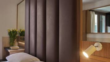 Una habitación de hotel con una cama grande, una mesita de noche con una lámpara y un espejo en la pared.