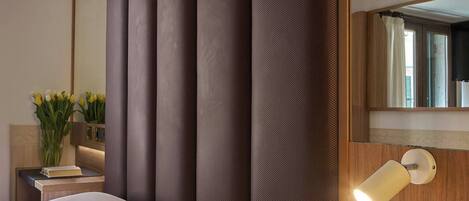 Una habitación de hotel con una cama grande, una mesita de noche con una lámpara y un espejo en la pared.