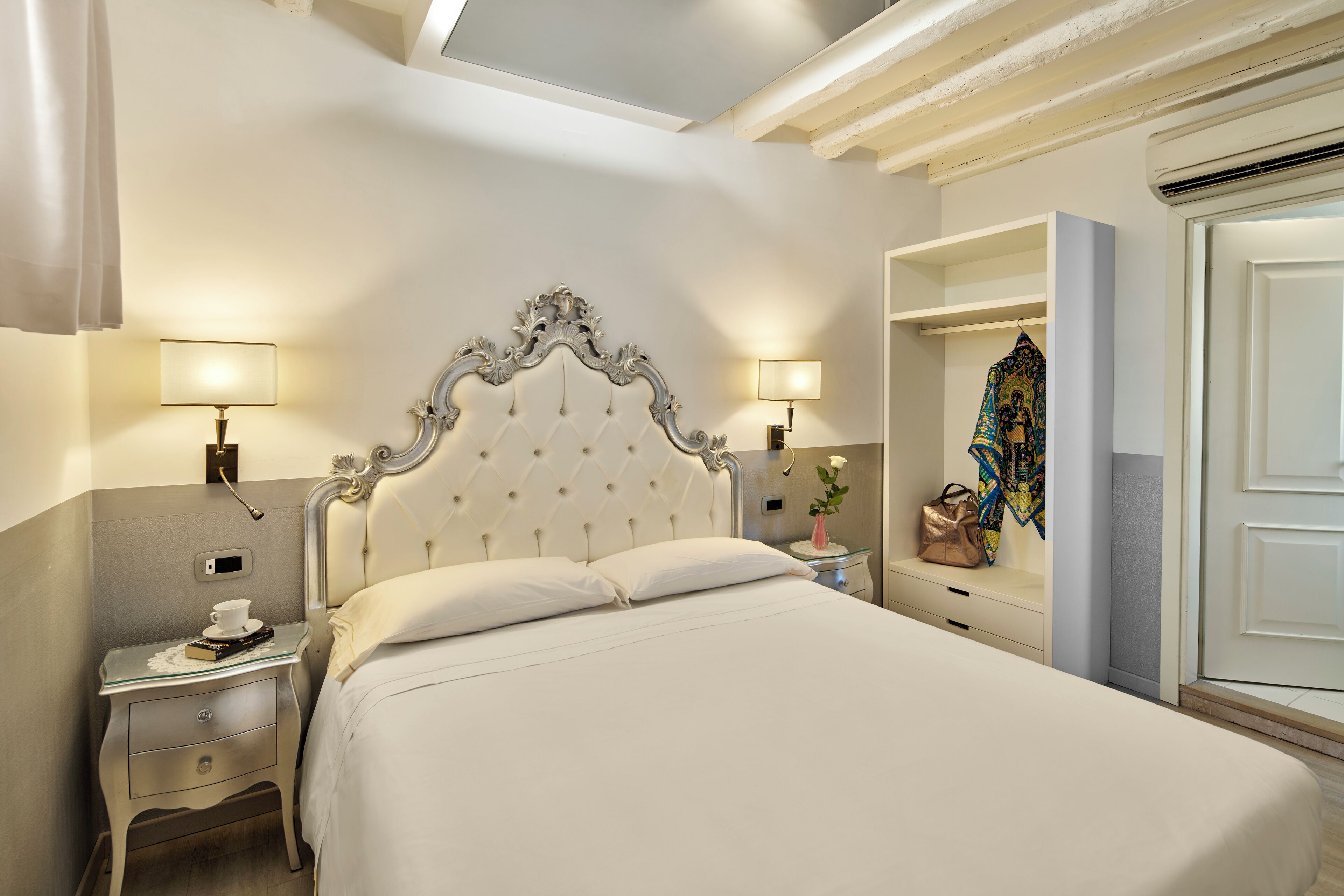 A neatly arranged hotel room with a large bed, bedside lamps, a nightstand, and a wardrobe.