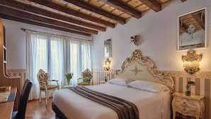A hotel room with a large bed, a desk with a chair, a small table with a lamp, and a mirror on the wall. - Unahotels Ala Venezia - Adults Only (Venice)