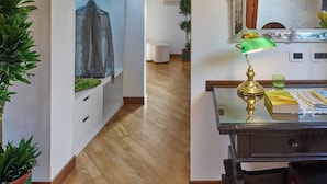 A room with a wooden floor, white walls, a desk with a lamp, a mirror, and a plant. - Unahotels Ala Venezia - Adults Only (Venice)