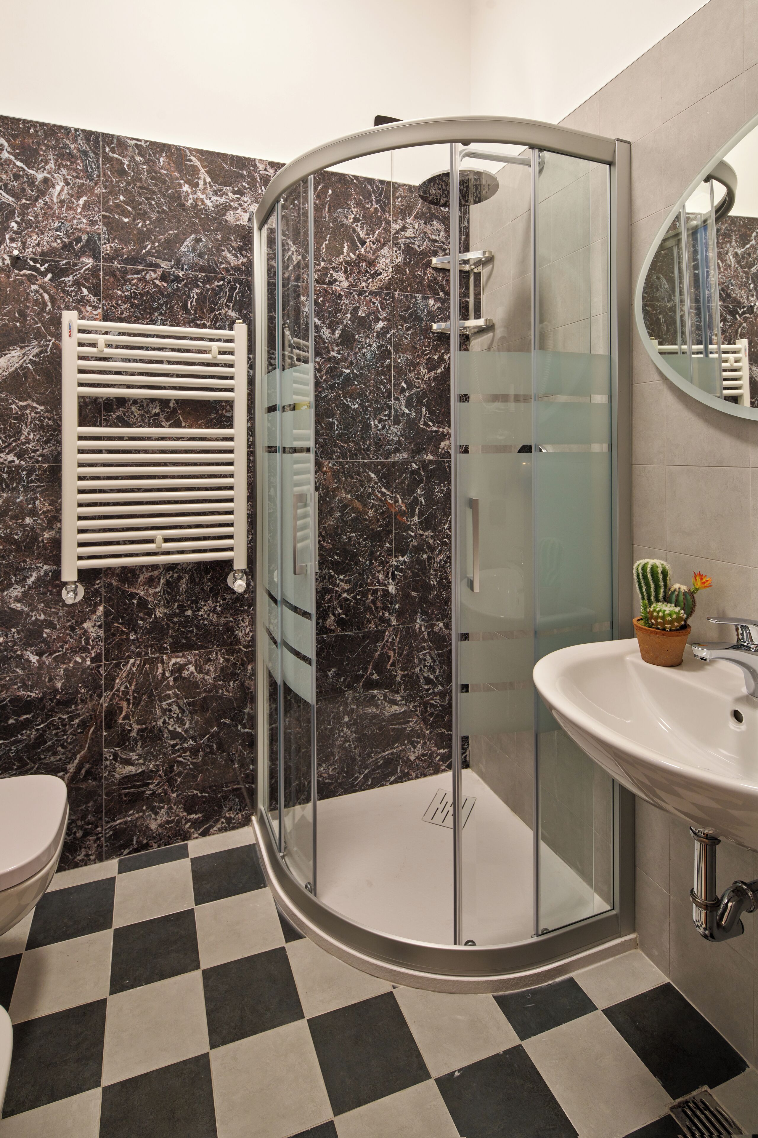 A bathroom with a glass-enclosed shower, a white sink, and a checkered floor.