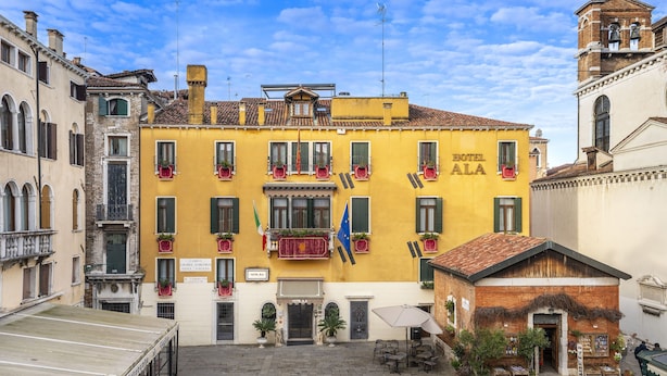 A yellow building with balconies, a sign reading "HOTEL ALA", and a flag. - Unahotels Ala Venezia - Adults Only (Venice)