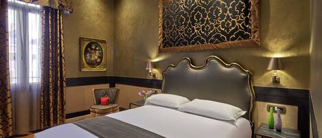 Une chambre d’hôtel avec un grand lit, une table de chevet avec une lampe, une chaise et un élément décoratif mural.