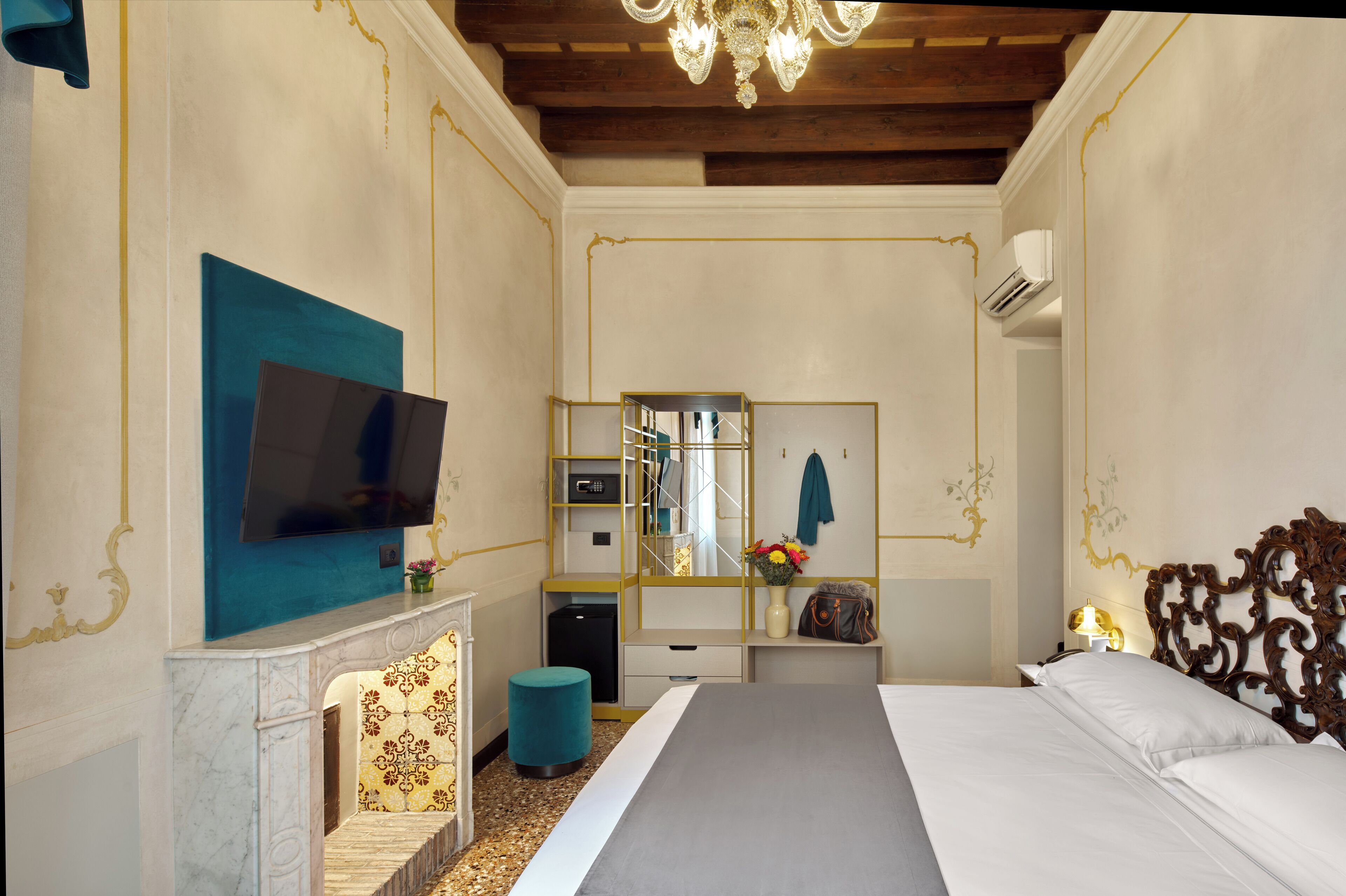Quarto de hotel com cama, televisão, espelho, secretária pequena e decoração na parede.