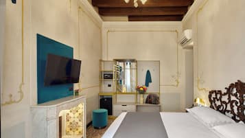 Una camera d'albergo con un letto, una televisione, uno specchio, una piccola scrivania e un elemento decorativo a parete.