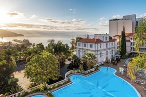 A hotel with a pool, a view of the sea, and a large building with a red roof. - Pestana Miramar Garden & Ocean Resort (Funchal)