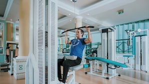 Academia com equipamentos de exercícios, incluindo uma barra de puxada e um banco.