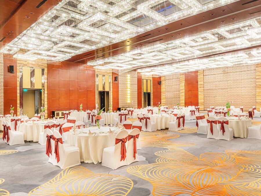 A large banquet hall with round tables, white tablecloths, and red sashes.