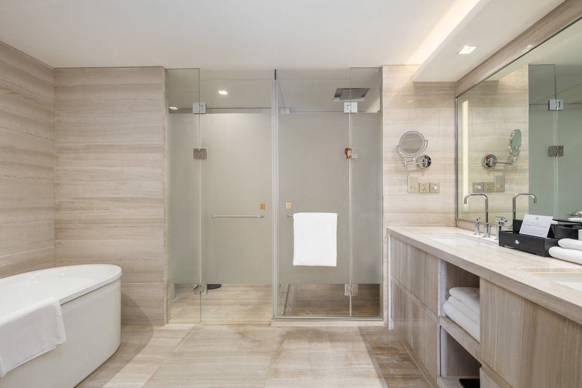 A modern bathroom with a glass-enclosed shower, a freestanding bathtub, and a vanity with a mirror and sink.