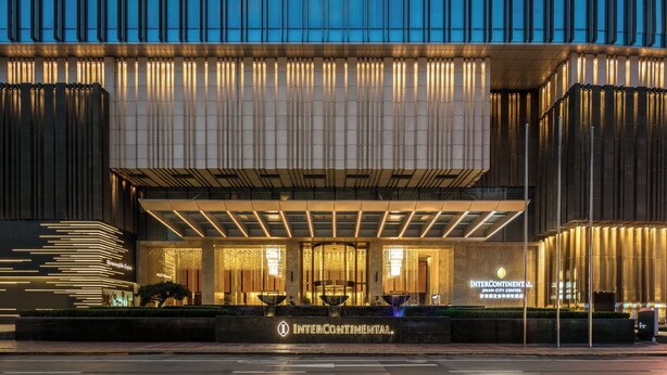 A modern building with a prominent entrance, illuminated signage, and a well-lit facade.