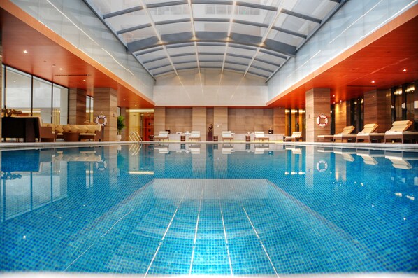 A large indoor swimming pool with a glass ceiling, lounge chairs, and a reception area. - InterContinental Jinan City Center by IHG (Jinan)