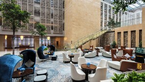 A spacious lobby with modern seating, a staircase, and a large glass facade.