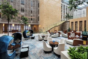 A spacious lobby with modern seating, a staircase, and a large glass facade.