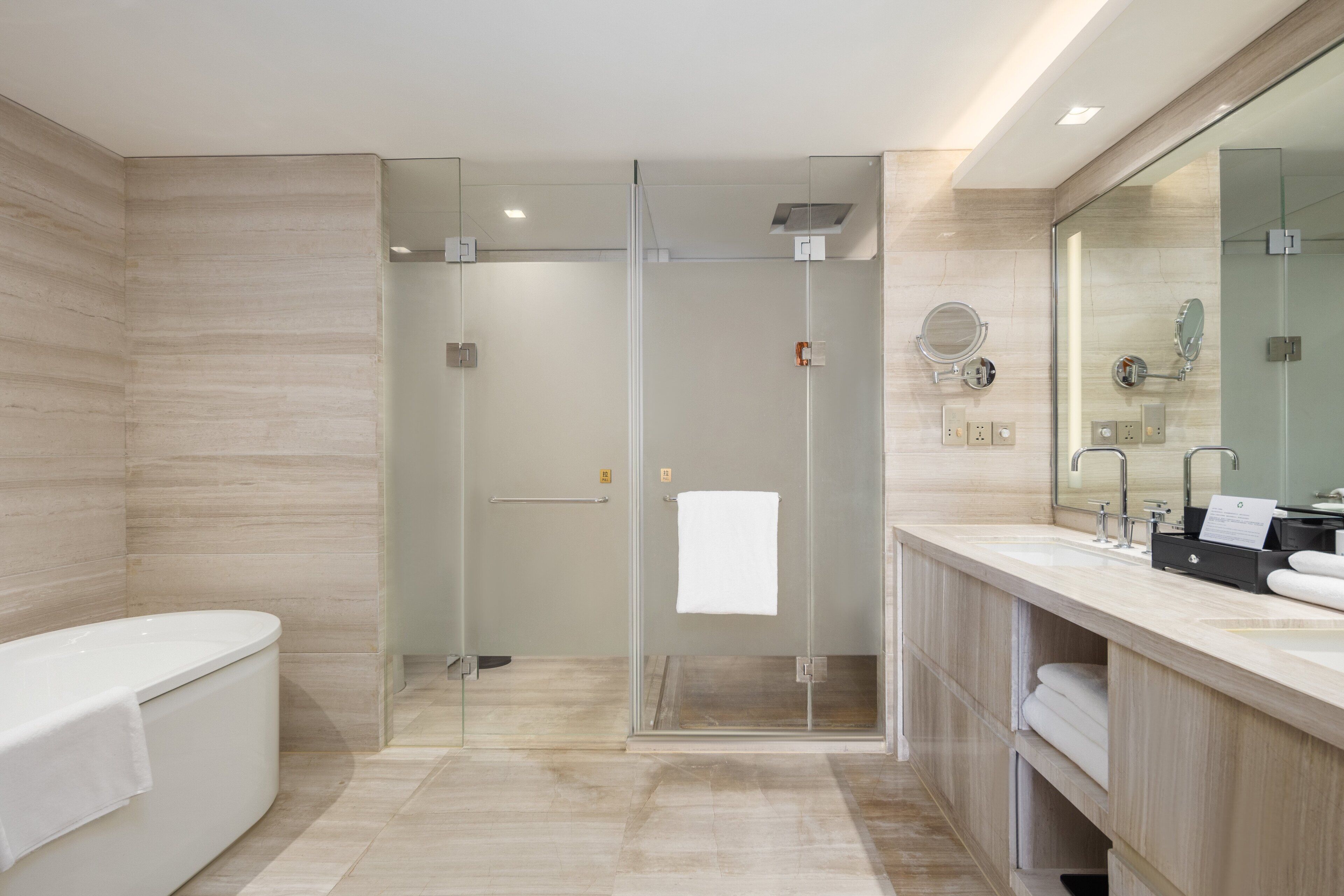 Un baño moderno con ducha de vidrio, bañera independiente y tocador con espejo y lavabo.
